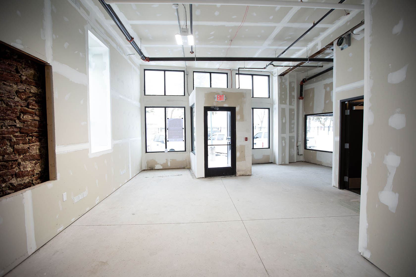 Renovated commercial interior with original stone walls, high ceilings, and storefront windows